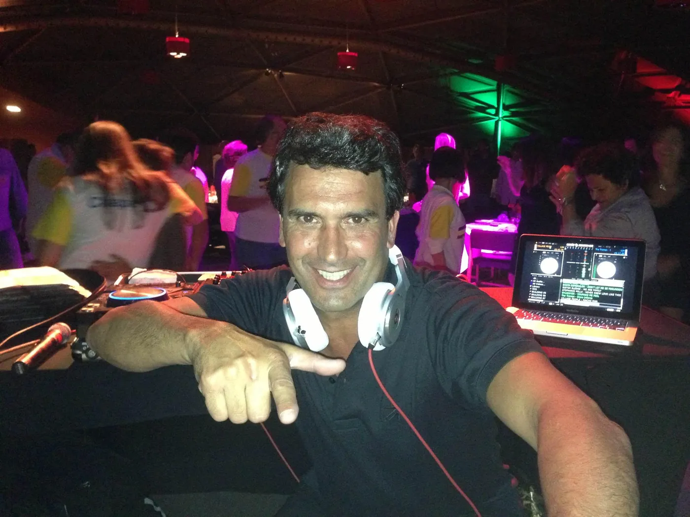 Nando Jones na cabine de DJ, sorrindo, com a pista lotada atrás