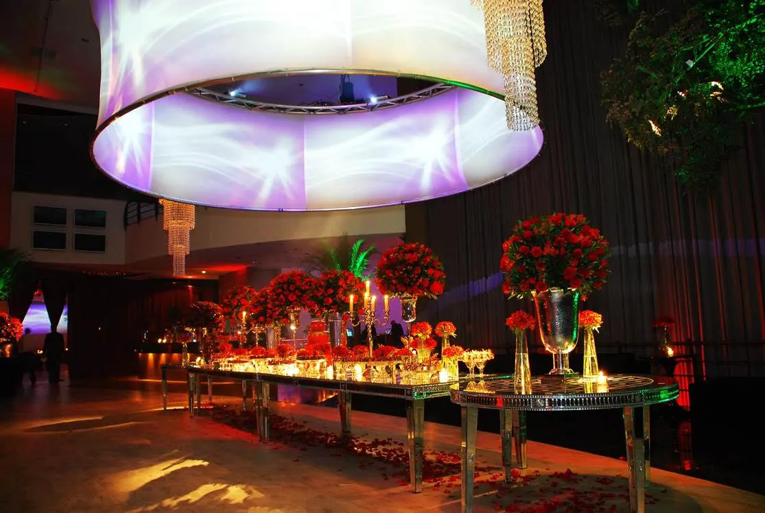 Buffet sob luminária cilíndrica com rosas vermelhas