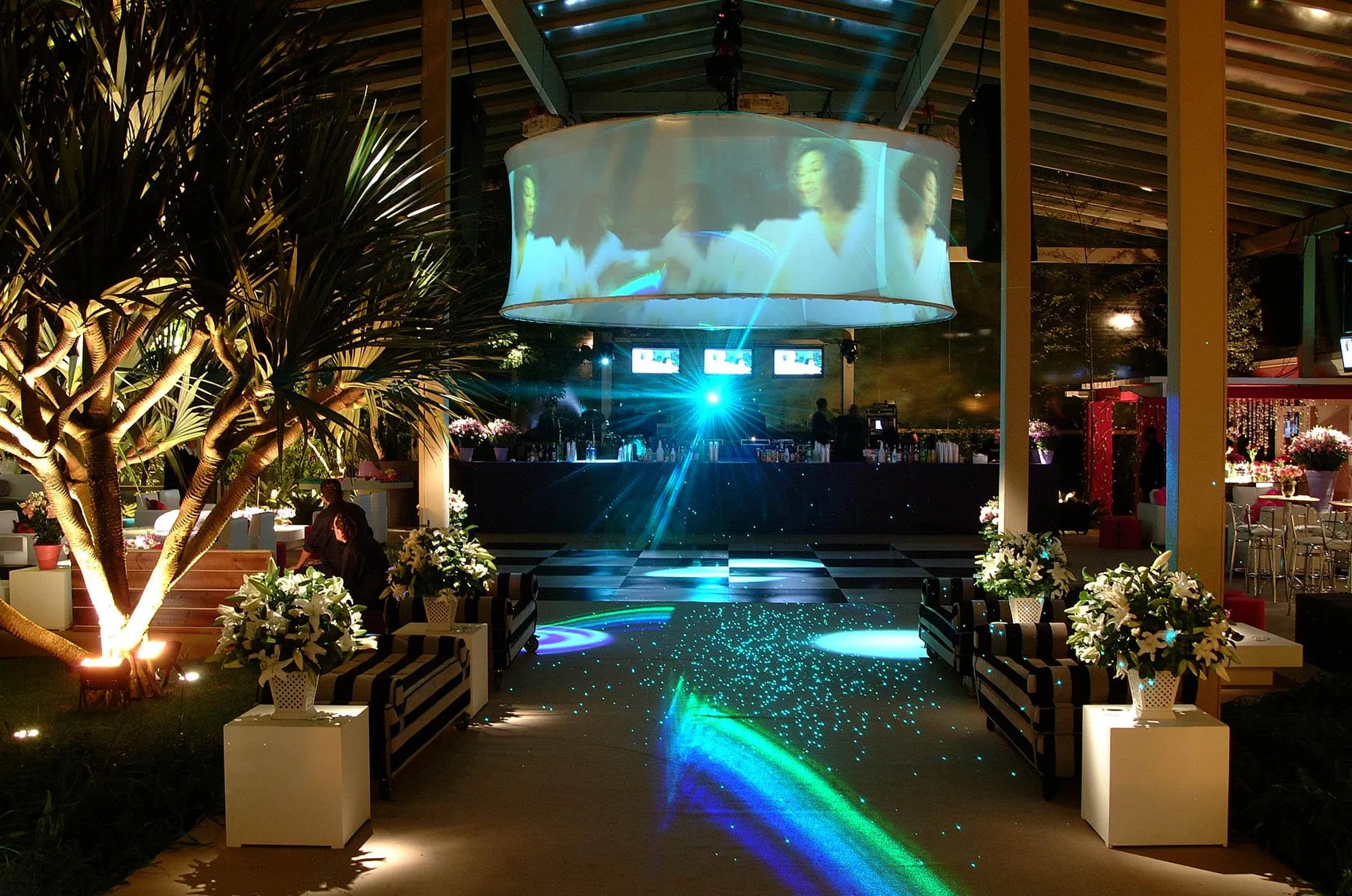 Festa noturna com lounge iluminado e telão suspenso